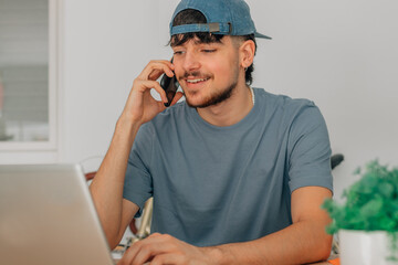 Canvas Print - young man or student at desk with computer or laptop and mobile phone