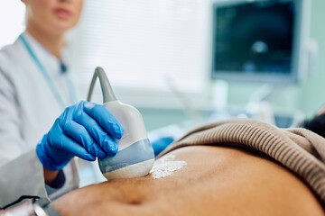 Wall Mural - Close up of doctor using ultrasound while examining black man's abdomen.