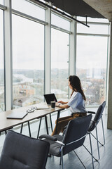 Wall Mural - Modern office woman worker in casual clothes works on a laptop. Female manager at workplace working on new project using laptop. modern workspace