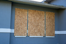Boarded Up Windows With Plywood Storm Shutters For Hurricane Protection Of Residential House. Protective Measures Before Natural Disaster In Florida