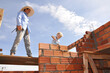 © Alexandre - avô e neto construindo parede de tijolos em construção