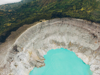 Top aerial view of turquoise sulfur water lake, surrounded by rock cliff at Kawah Ijen volcano in East Java, Indonesia.