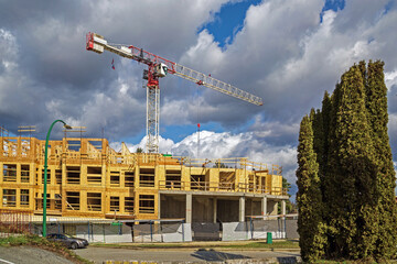 Wall Mural - Construction wooden apartment building, construction crane on a background of cloudy sky in Coquitlam City