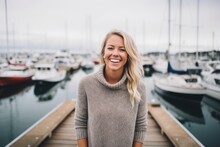 Medium shot portrait photography of a grinning woman in her 30s that is wearing a cozy sweater against a bustling marina with yachts and sailboats background .  Generative AI