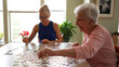 © Robert Peak - Happy smiling, laughing elderly senior woman sitting at table with mature middle aged daughter working on puzzle
