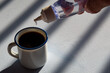 person sweetening coffee with liquid sweetener