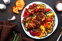 Grilled Chicken Fillet And Vegetables Salad. Colorful Paprika, Zucchini, Eggplant, Mushrooms, Tomatoes, Red Onion With Rosemary, Served On Plate, Brown Table Background, Top View