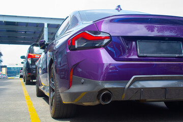 Wall Mural - back view of purple sedan bmw cars parking in a row with yellow line on the ground. low angle view