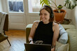 © Kostiantyn - Smiling woman using laptop for online learning or watching movie while lying on sofa at home