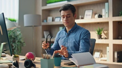 Wall Mural - Tired man rubbing eyes at computer work place. Artist drinking coffee stretching