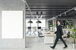 © Who is Danny - Front view of blank white isolated poster on a light grey wall at the entrance to modern loft office interior with concrete floor and walking businessman on window city view background. Mockup