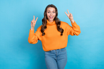 Poster - Photo of sweet excited lady dressed orange pullover showing two v-signs isolated blue color background