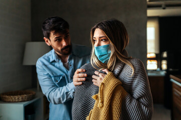 Young woman suffering with cold and flu, cancer. Husband taking care of his sick wife