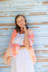 Portrait of beautiful caucasian senior woman with hand on chin standing against wooden wall