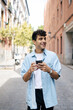 © Imanol - Young man with curly hair using smartphone