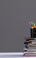 Wall Mural - Stack of books and notebooks with pencil container on top and copy space on grey background