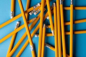 Canvas Print - Close up of stack of yellow pencils with erasers on blue background