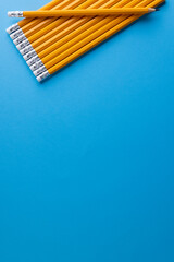 Canvas Print - Close up of yellow pencils with erasers and copy space on blue background