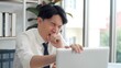 © M Stocker - Exhausted young asian worker yawning at workplace. Business man using laptop for working feeling sleepy and yawning tired from overwork job