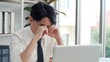 © M Stocker - Young Asian man tired eyes from hard work. Young man tired feeling eyestrain stressed working from laptop. Suffers eyesight problem after using laptop for working long time
