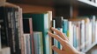 © M Stocker - Close up hand search for book on bookshelves in the library. Select a book on shelf. Studying knowledge education in bookstore