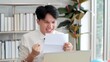 © M Stocker - Young Asian man received great news highest mark successfully pass exams or test. Asian man Read paper notice with feels happy excited, celebrate university admission