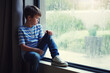 © Alex Ford-Robertson/peopleimages.com - Boy child, rain and sad by window with thinking, mental health and space for mockup in home. Male kid, raining and think by glass with depression, mock up or bored with problem, winter or frustration
