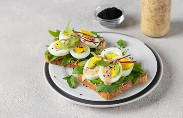 Homemade sandwiches with egg, arugula and cheese sprinkled with sesame seeds on round plate