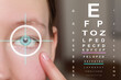 Vision test chart and laser reticle focused on woman's eye against blurred background, closeup