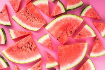 Wall Mural - Watermelon slices arranged on high-colored pink background. Simple basic summer harvest and holiday background, top view flat lay banner copy space