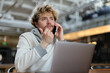 © Andrii Zastrozhnov - Curly bearded male freelancer talking on the phone while working on a laptop.