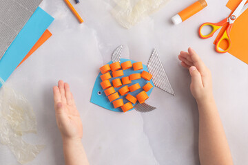 paper adorable fish with children at home. hands making diy summer crafting. ocean's day.