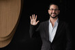 © Ranta Images - Portrait of handsome businessman against black background greeting