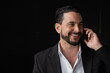 © Ranta Images - Portrait of handsome businessman against black background smiling and talking on phone
