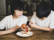 © Jatuporn - Two asian brother decorate their meat egg and ketchup with vintage style picture