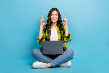 Poster - Full length portrait of cheerful pretty person sit floor use netbook look direct fingers up empty space isolated on blue color background