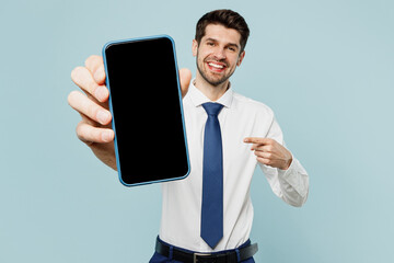 Young employee business man corporate lawyer wear classic formal shirt tie work in office hold use show blank screen workspace area mobile cell phone isolated on plain blue background studio portrait.