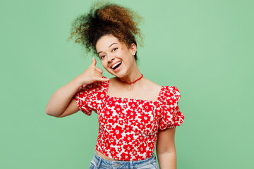 Young fun smiling happy woman she wear casual clothes red blouse doing phone gesture like says call me back isolated on plain pastel light green color background studio portrait. Lifestyle concept