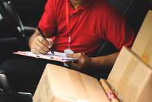 Hand Of Delivery Man Checking Shipment Documents While Sitting In Driver Seat Of Van. Business Cargo Express And Delivery Service Concept