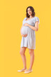 © Pixel-Shot - Young pregnant woman on yellow background