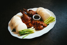 Peking Duck With Chinese Pancakes, Scallions And A Dipping Sauce On A White Platter Against A Black Background