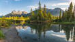 Mountain peaks reflecting in the calm water below at Three Sisters in Canmore, near Banff National Park, Canada in summer time with wilderness, wild, tourist, tourism area.