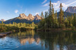 Landscape view of Three Sisters in Canmore during summer time. Unreal, surreal massive mountain peaks at sunset, reflecting in water below. Banff National Park, Canada.