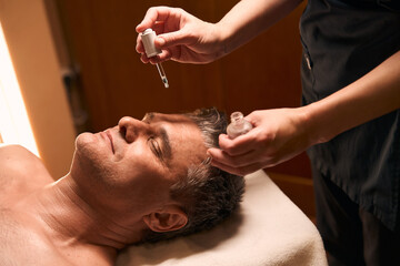 Wall Mural - Experienced masseuse preparing client for facial massage