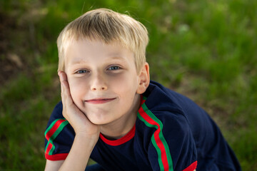 Wall Mural - Portrait of a little boy in a blue t-shirt posing in a summer park