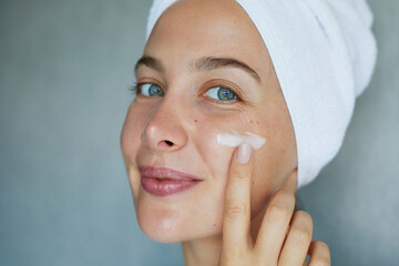 Morning skin care routine. Young beautiful woman is applying  a cream, scrub beauty product on her face. Domestic daily skincare