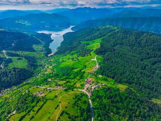 Wall Mural - Bicaz lake and green meadow, aerial view. Potoci, Romania, summer scene