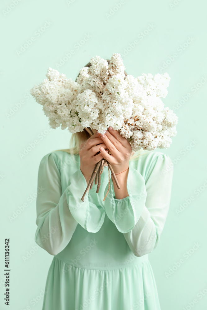 Young woman with lilac flowers on green background