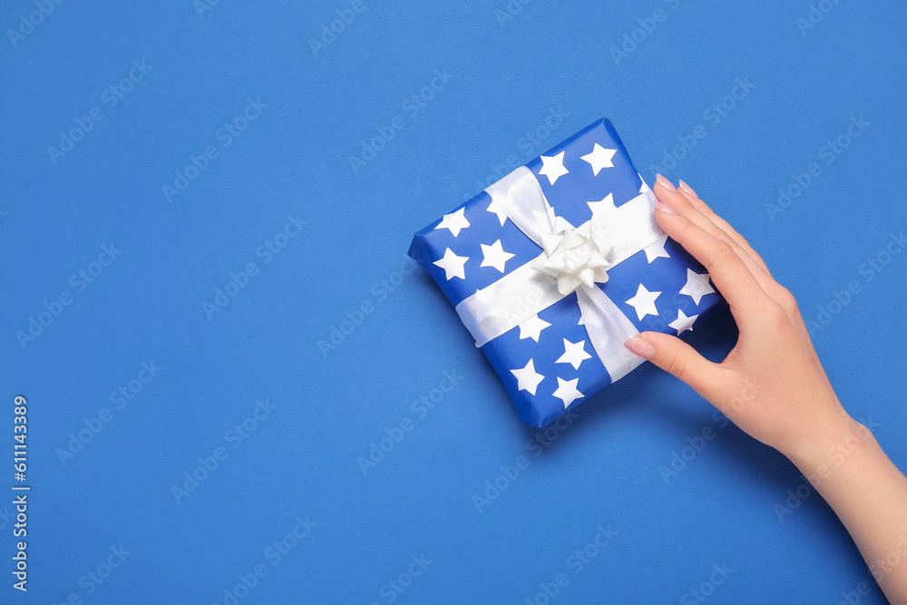 Woman holding gift box for American Independence Day on blue background