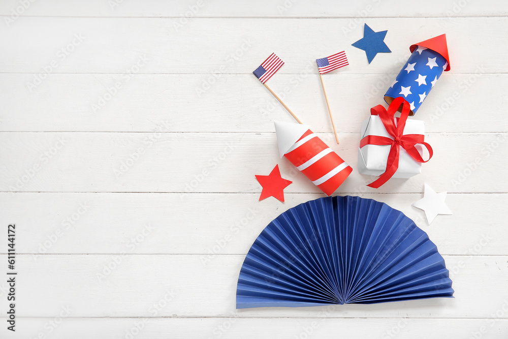Gift box with USA flags, firework rockets and fan on white wooden background. American Independence Day